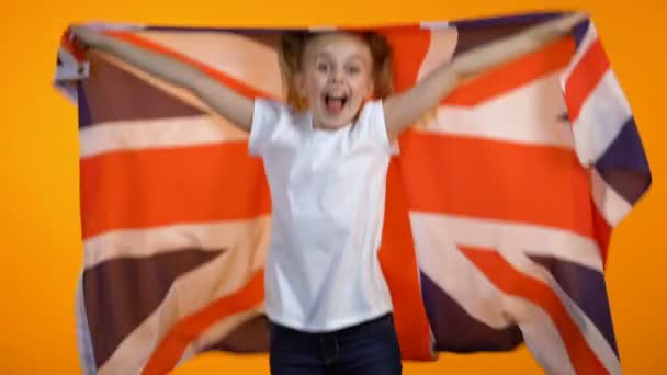 Smiling teen girl jumping with british flag, cheering for national football team - Кадры, видео