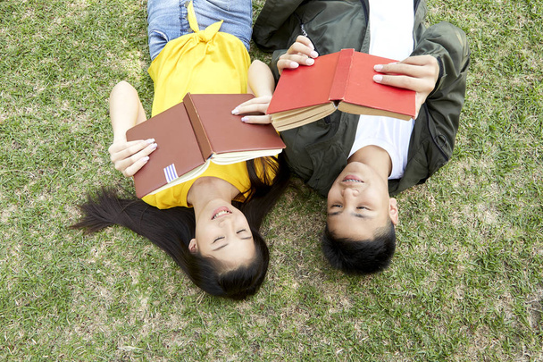 Підлітки з книгами лежать на зеленій траві
 - Фото, зображення