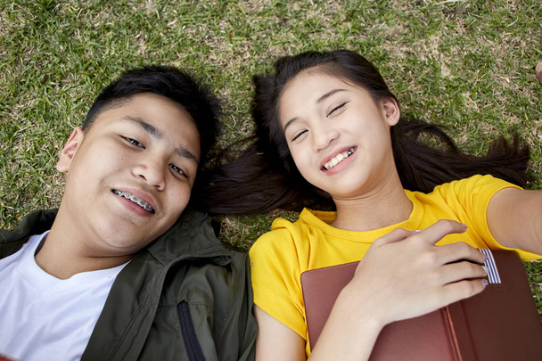 Les adolescents avec des livres couchés sur l'herbe verte
 - Photo, image