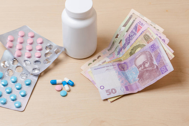 Medikamente, blaue und rosa Pillen und ukrainisches Geld auf dem Tisch - Foto, Bild