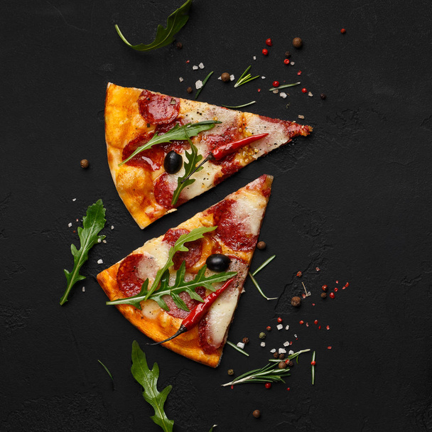 Pizza slices with rocket salad on black background - Valokuva, kuva