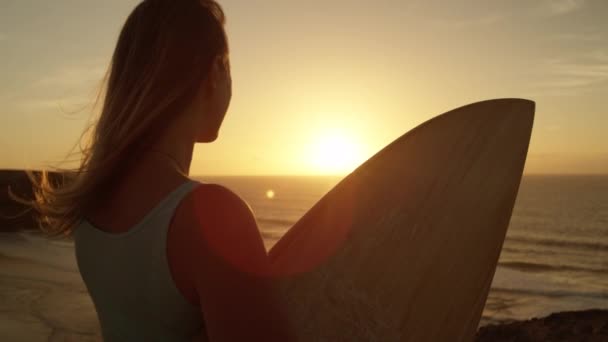 Pomalý pohyb: ženy surfař obdivují večerní scenérie v dálce. Surferova dívka držící surfu a zírala na mesmerující oceán. Žena sportovec užívající letní prázdniny v Fuerteventuře. - Záběry, video