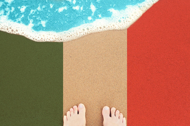 Stopy na słonecznej piaszczystej plaży z flagą Włoch. Widok z góry  - Zdjęcie, obraz