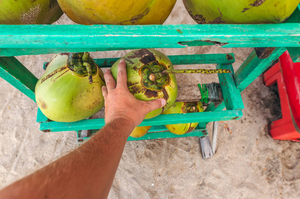 Man hand met groene biologische kokosnoot op het strand van Bali eiland, Indonesië. Kuta Beach. - Foto, afbeelding