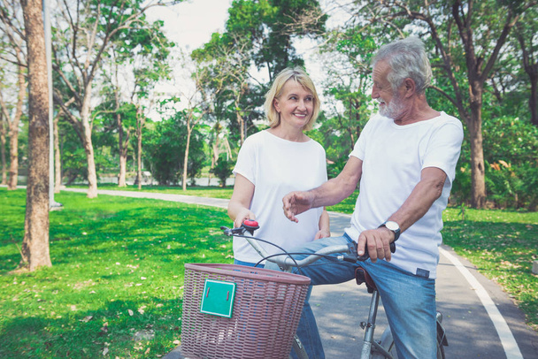Happy elder couple riding a bicycle in the park - Foto, immagini