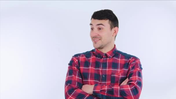 Arrogante jonge man dragen Plaid rood hemd wijzend vinger aan iemand en glimlach wordt verrast geïsoleerd over witte achtergrond. - Video