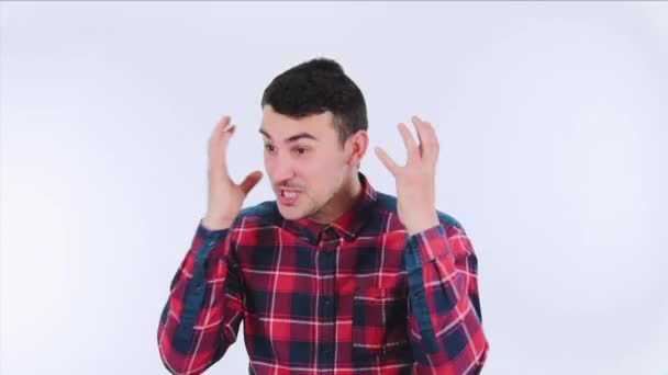 Stressed young man screaming isolated over white background. Casual angry guy hands to head having troubles being unlucky. Annoyance and depression feeling. - Felvétel, videó