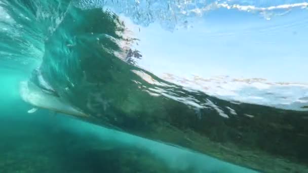 Podwodne Slow Motion nierozpoznawalny ekstremalne surfer jazda szklisty baryłkę fali w krystalicznie czyste Ocean w słoneczny dzień. Pro surfing kochanka poślizgiem rękę na fali, jak jeździ przez. Zabawne letnie wakacje - Materiał filmowy, wideo