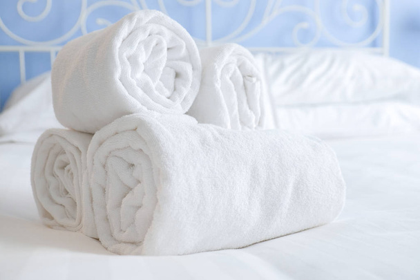 frische und saubere schön zusammengerollte Handtücher liegen auf einem Bett - Foto, Bild