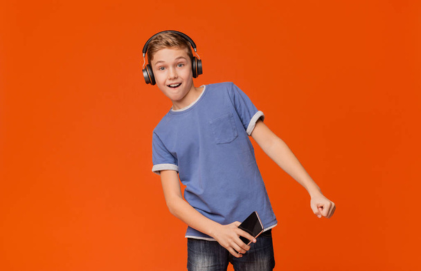 Leuke jongen in de koptelefoon te luisteren naar muziek op de telefoon - Foto, afbeelding