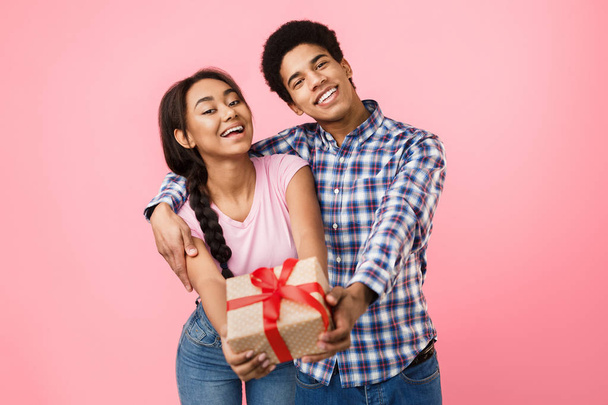 Подростковая пара радуется, протягивая подарочную коробку к камере
 - Фото, изображение