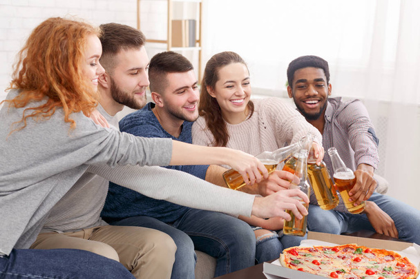 Zusammentreffen feiern. Freunde klappern zu Hause mit Bierflaschen - Foto, Bild