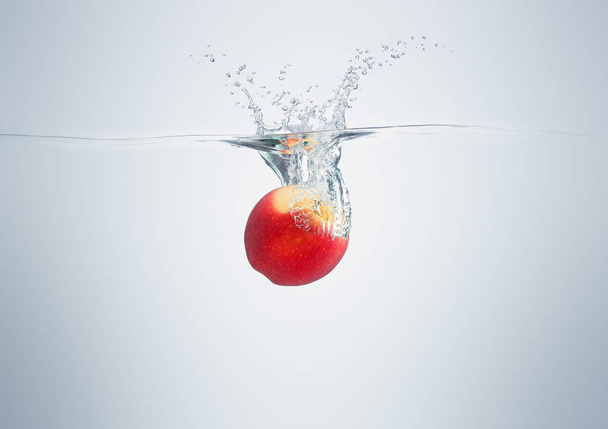 apple falls into the water scattering a lot of splashes and drop - 写真・画像