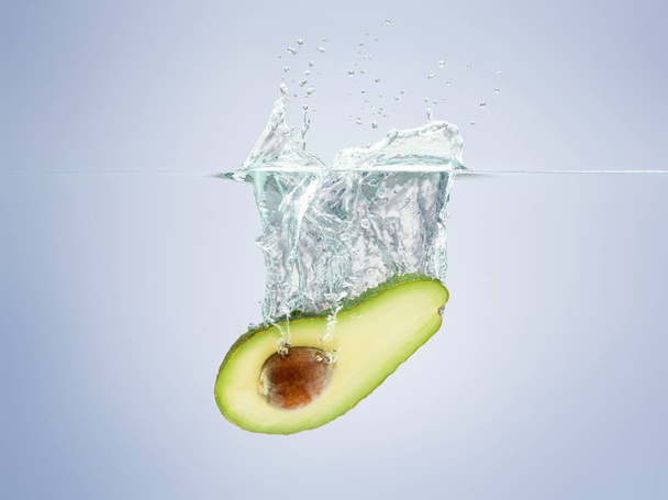 avocado drops in the water scattering a lot of sprays and drops - Foto, Bild