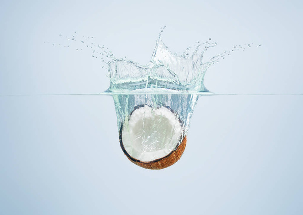 coconut falls into the water scattering a lot of splashes and dr - Foto, afbeelding