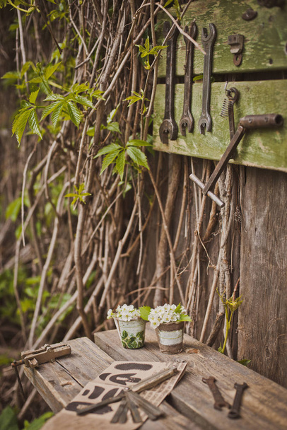 design of the photo zone in a rustic style, old wooden doors and boards with tools and spring flowers. - Photo, Image