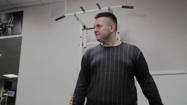 Der gut gelaunte dicke Mann macht im Fitnessstudio eine falsche Übung. zum ersten Mal in einem Fitnessclub. - Filmmaterial, Video