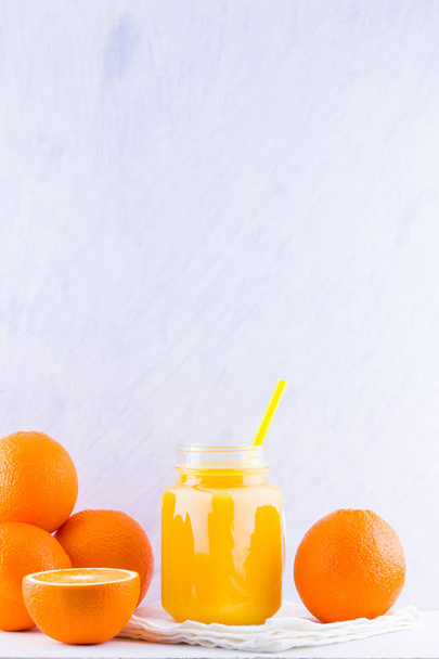 Frutas de laranja e suco no fundo branco. Frutas cítricas para fazer suco com espremedor manual. Laranjas em guardanapo branco. Frasco Mason com suco de laranja
 - Foto, Imagem
