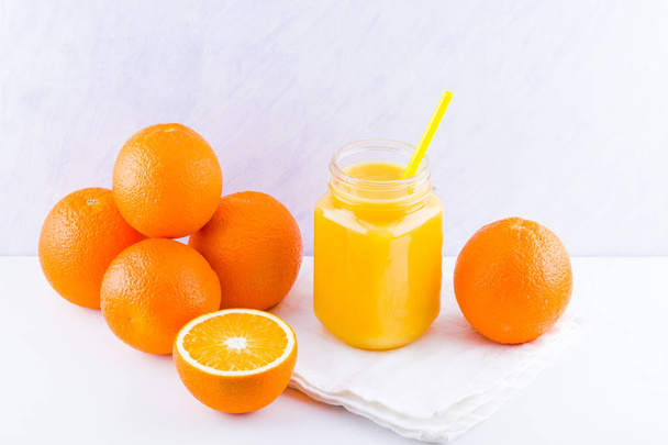 白の背景にオレンジ色の果物やジュース。手動ジューサーでジュースを作るための柑橘系の果物。白ナプキンにオレンジオレンジジュースのメイソンジャー - 写真・画像