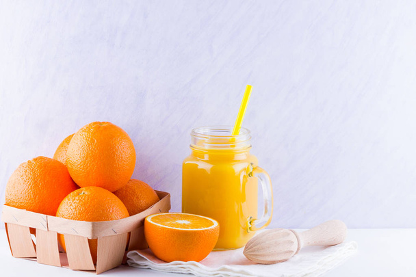 Orange fruits and juice on white background. Citrus fruit for making juice with manual juicer. Oranges in wooden box on white napkin. Mason jar with orange juice - 写真・画像