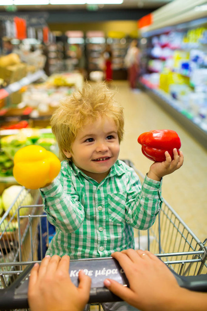 Child with mom on purchases shopping. Supermarket and menu for a family dinner. Family, diet, nutrition. Vegetables, pepper, healthy diet. Losing weight for mom. Beautiful baby with vegetables - Photo, Image