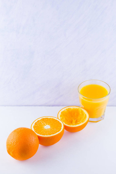 Orange fruits with juice, concept. Orange juice and halves of oranges on white background. Citrus for making juice. Whole and squeezed oranges and glass of juice - Фото, зображення