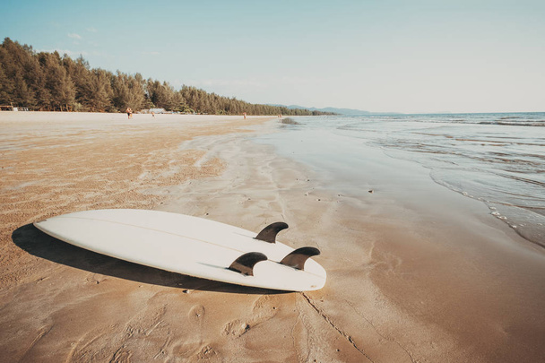 Tavola da surf sulla spiaggia tropicale di sabbia con mare calmo e sfondo cielo. vacanze estive sfondo e sport acquatici concetto. effetto tono colore vintage
. - Foto, immagini