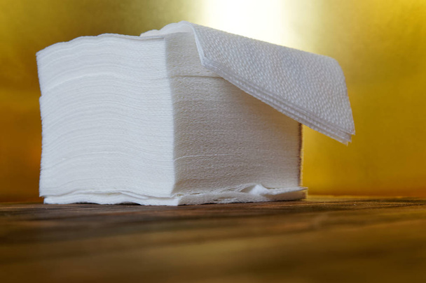 Una pila de servilletas de papel higroscópicas sobre un fondo dorado y una superficie de madera
.  - Foto, imagen