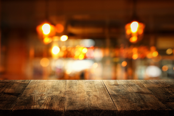 Image of wooden table in front of abstract blurred restaurant lights background - Foto, imagen
