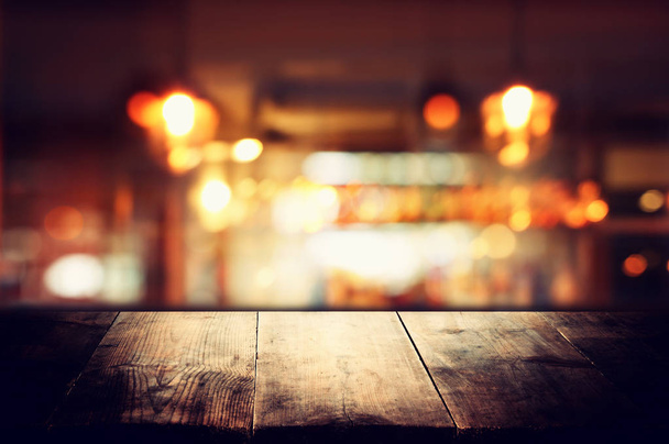 Image of wooden table in front of abstract blurred restaurant lights background - Photo, Image