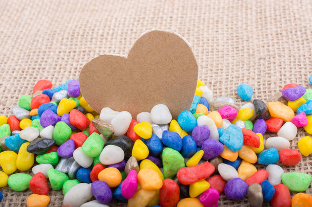 Paper heart amid pebbles on canvas ground - Photo, Image