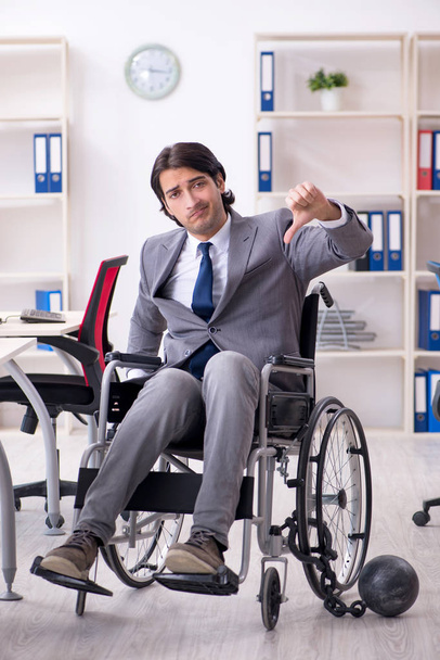 Jovem e bonito funcionário em cadeira de rodas trabalhando no escritório
   - Foto, Imagem