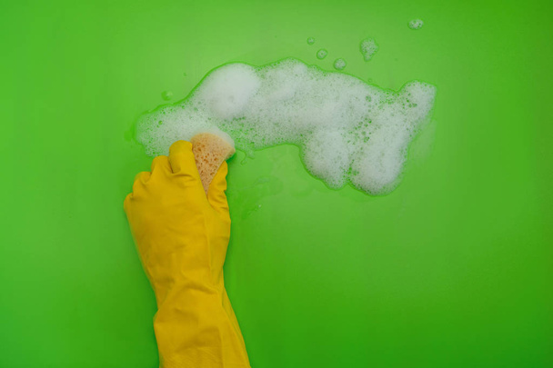 Huishoudelijk concept. Hand in geel beschermende rubberen handschoen wassen glazen venster met spons en wasmiddel schuim. Ruimte kopiëren - Foto, afbeelding