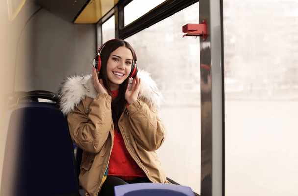 Young woman listening to music with headphones in public transport - Photo, Image