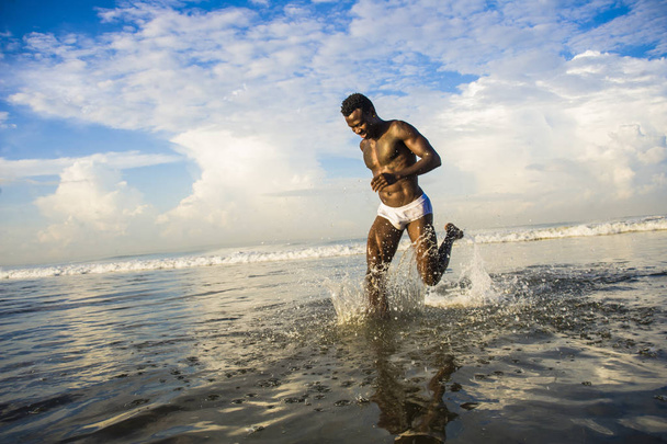 heureux et attrayant noir homme afro-américain en forme corps sain et musclé en cours d'exécution sur la plage de l'eau de mer s'amuser profiter des vacances d'été se sentir libre
 - Photo, image