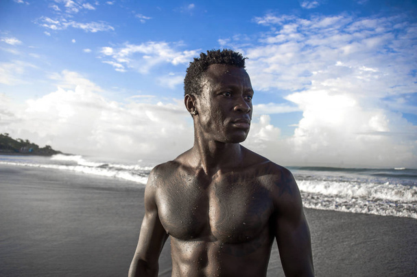 portrait of young attractive and fit black African American man with strong muscular body posing cool model attitude on the beach isolated on Summer blue sky - Фото, зображення