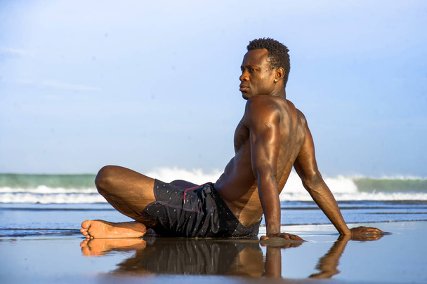 young attractive and relaxed black afro American man with fit body and muscular back sitting on beach sand enjoying beautiful view thinking and meditating free - Foto, afbeelding
