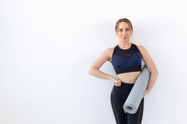Люди, фітнес і спортивна концепція - приваблива і здорова жінка тримає сірий килимок на білому тлі з місцем для тексту
 - Фото, зображення