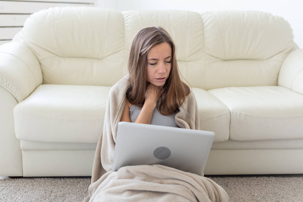 Mulher com uma dor de garganta sentado no chão com laptop
 - Foto, Imagem