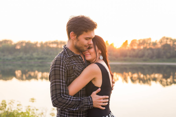 Relatie, de liefde en de natuur concept - aantrekkelijke vrouw en knappe man knuffelen en zoenen over water achtergrond - Foto, afbeelding