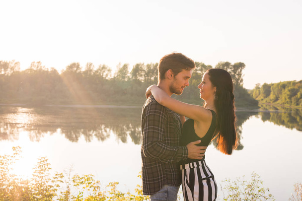 People, love and nature concept - Portrait of young beautiful couple embracing each other while standing over nature background - Fotoğraf, Görsel
