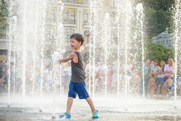 garoto animado se divertindo entre jatos de água, na fonte. Verão i
 - Foto, Imagem