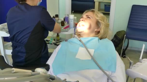 Киев, Украина - апрель 2019: Девушка на приеме у стоматолога. Стоматолог лечит пациента в стоматологическом кабинете. Стоматолог лечит пациента в клинике
. - Кадры, видео