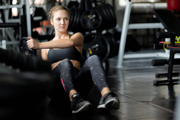 Fit beautiful young woman caucasian doing exercise at indoor workout in gym. Young woman holding dumbbell during an exercise class in a gym. Freedom happy and relax lifestyle healthcare concept. - Foto, immagini