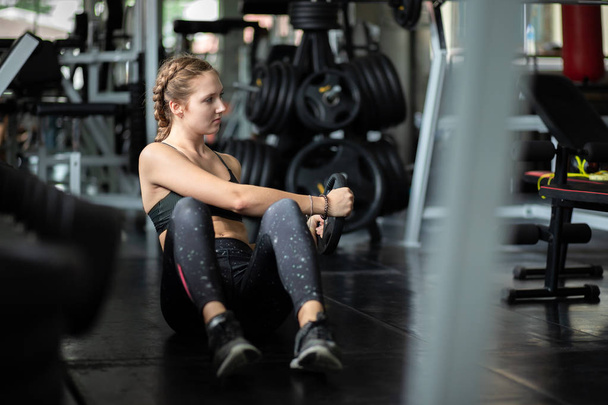 Fit beautiful young woman caucasian doing exercise at indoor workout in gym. Young woman holding dumbbell during an exercise class in a gym. Freedom happy and relax lifestyle healthcare concept. - Photo, Image