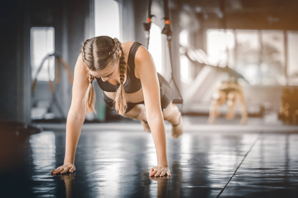 Portret jonge aantrekkelijke gezonde vrouw lichaamscurve fitness doen push-up bij indoor workout in de sportschool. Mensen schoonheid perfecte lichaam slank fitness meisje. Vrijheid gelukkig en ontspannen levensstijl gezondheidszorg concept. - Foto, afbeelding