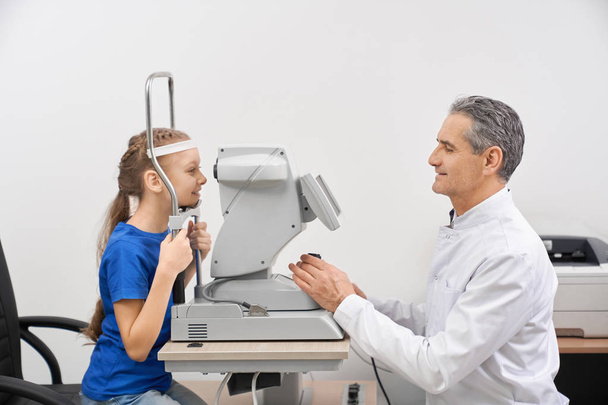 Medical worker checking eyesight of little girl in clinic - Foto, Bild