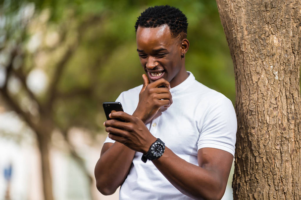 Outdoor portrait of a Young black African American men texting   - 写真・画像