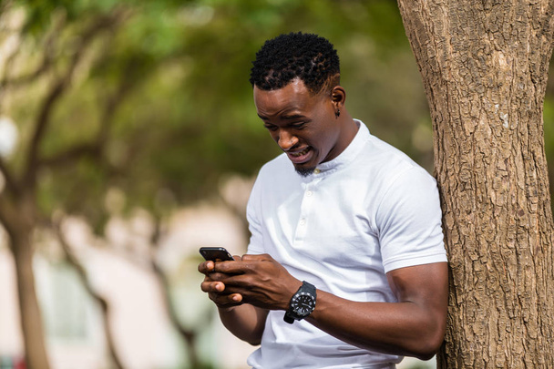 Outdoor portrait of a Young black African American men texting   - Fotografie, Obrázek