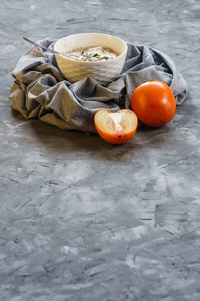 Oatmeal with Persimmon on a Gray Rough Surface - Фото, изображение